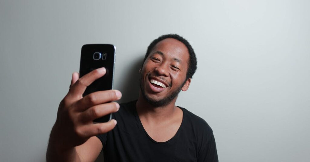 Man Holding Smartphone While Leaning on White Wall